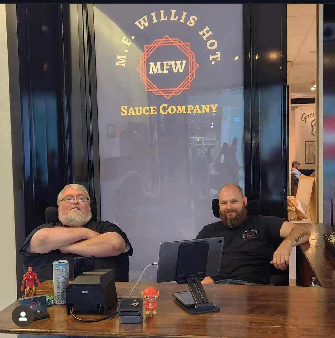 Two men relaxing in front of M.F. Willis Hot Sauce Company, preparing for a big moving day.